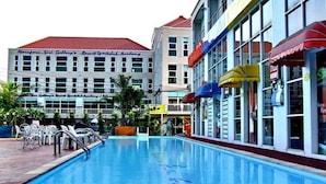 A swimming pool with lounge chairs and umbrellas, surrounded by buildings with signage for a resort and hotel. - Nsiri Resort & Hotel (Lam Luk Ka)