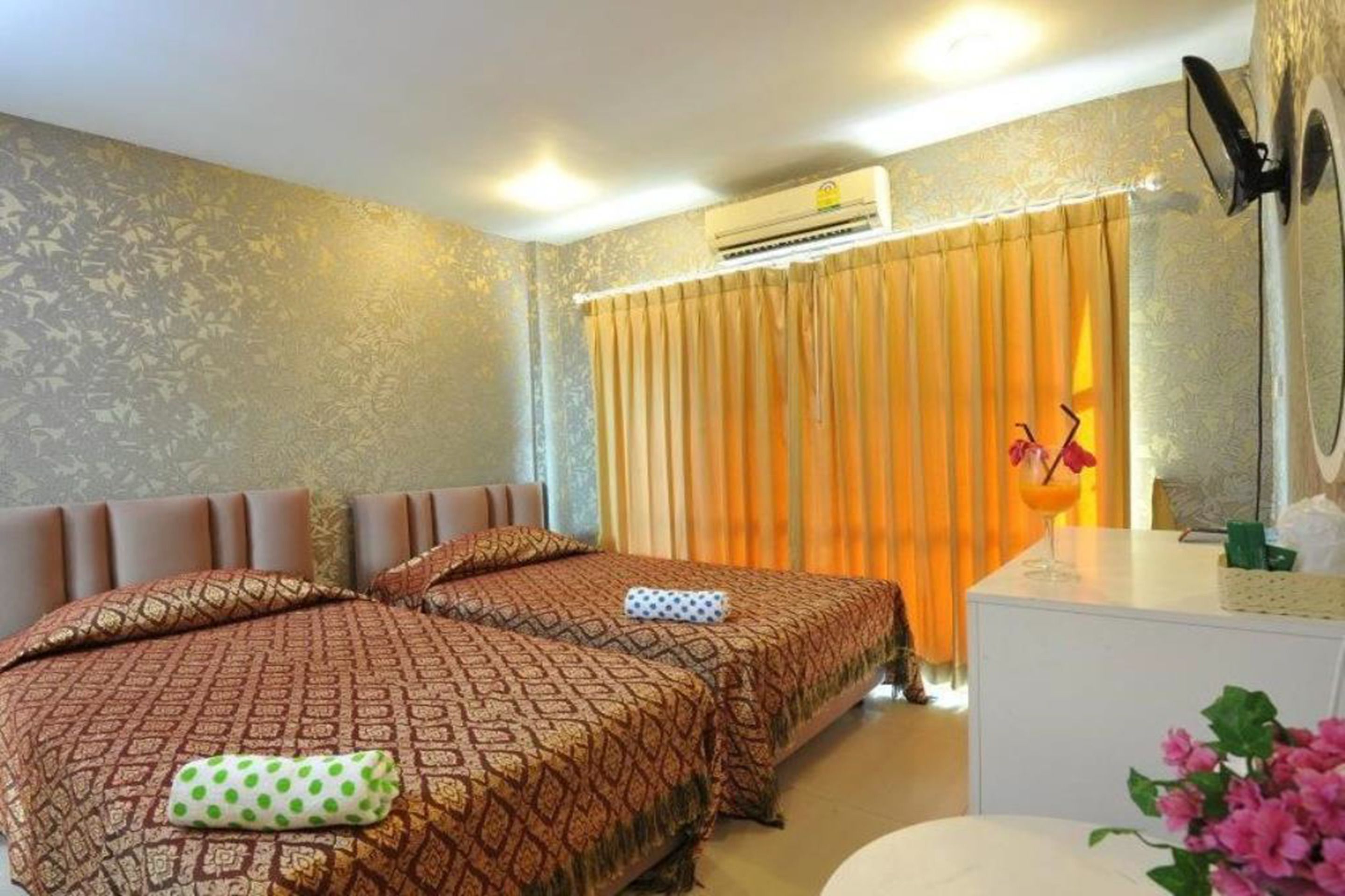 Habitación de hotel con dos camas, un tocador blanco, un equipo de aire acondicionado y una cortina.