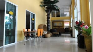 A spacious lobby with a high ceiling, a palm tree, and a seating area with chairs and tables. - Nsiri Resort & Hotel (Lam Luk Ka)