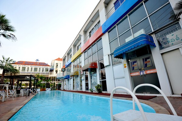 A swimming pool with a poolside area, a covered seating area, and a building with multiple storefronts including a Fresh Mart. - Nsiri Resort & Hotel (Lam Luk Ka)