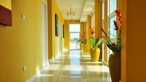A bright hallway with yellow walls, a chandelier, and large vases with flowers. - Nsiri Resort & Hotel (Lam Luk Ka)