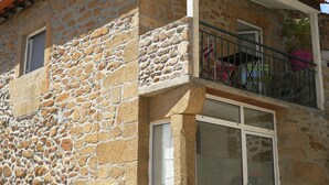 Un edificio in pietra con un balcone, finestre e una porta.