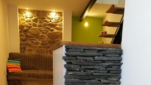 Un'area reception con parete in pietra, pavimento in legno e una poltrona con cuscini colorati.