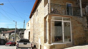 Un edificio in pietra con un balcone e un'ampia porta in vetro.