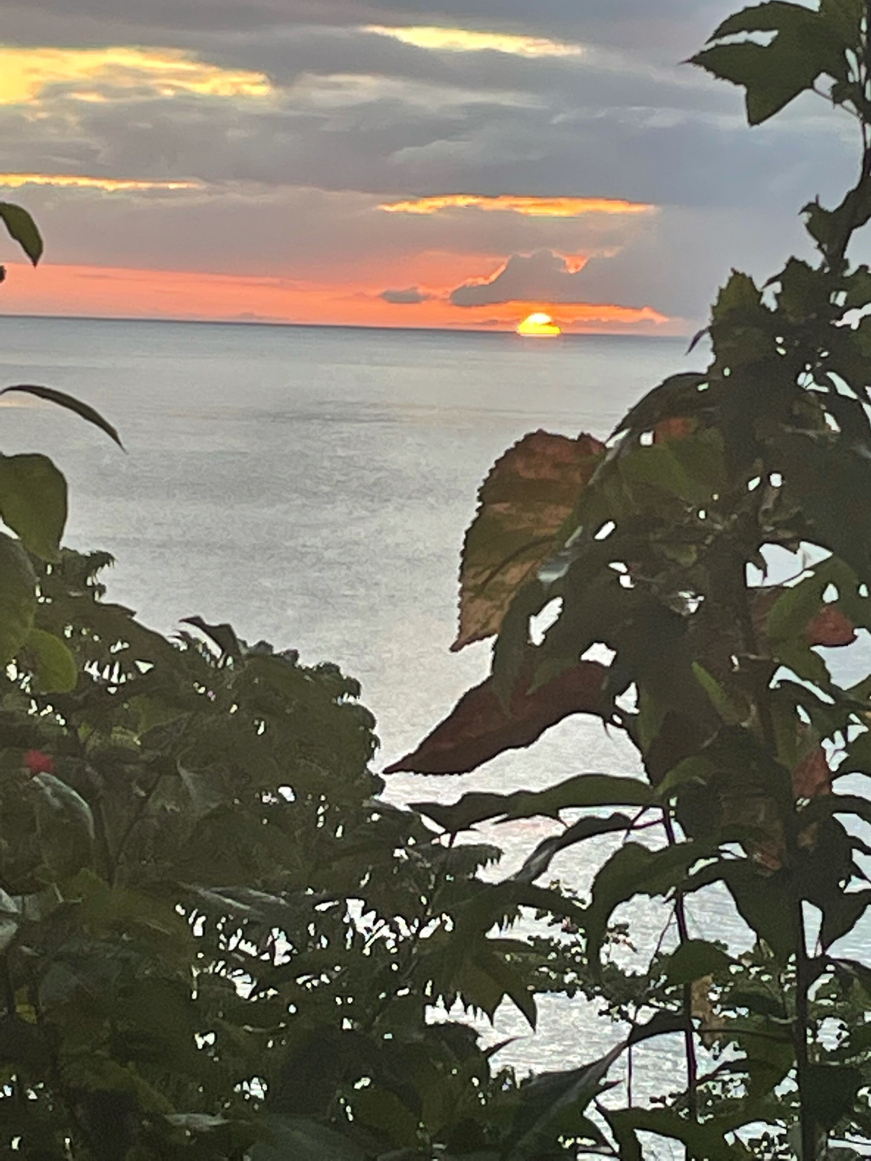 A sunset over a calm sea with a view of the horizon.