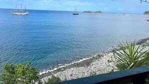 Vista costera con un barco y un litoral rocoso.
