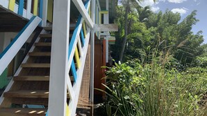 Una escalera con barandilla blanca, azul y amarilla que lleva a un espacio exterior cubierto.