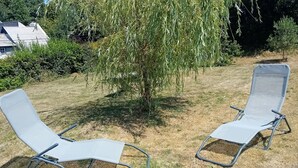 Two outdoor lounge chairs in a grassy area with a tree and a building in the background. - house near shops, small echo of the pond Mode 5 ha 15 minutes from the sea, hiking (Châtelaudren)