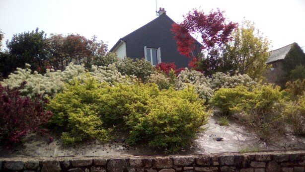 A stone wall with a garden in front of a house. - house near shops, small echo of the pond Mode 5 ha 15 minutes from the sea, hiking (Châtelaudren)