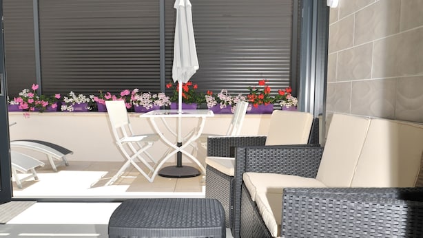 Un patio al aire libre con muebles de mimbre, una mesa y sillas.