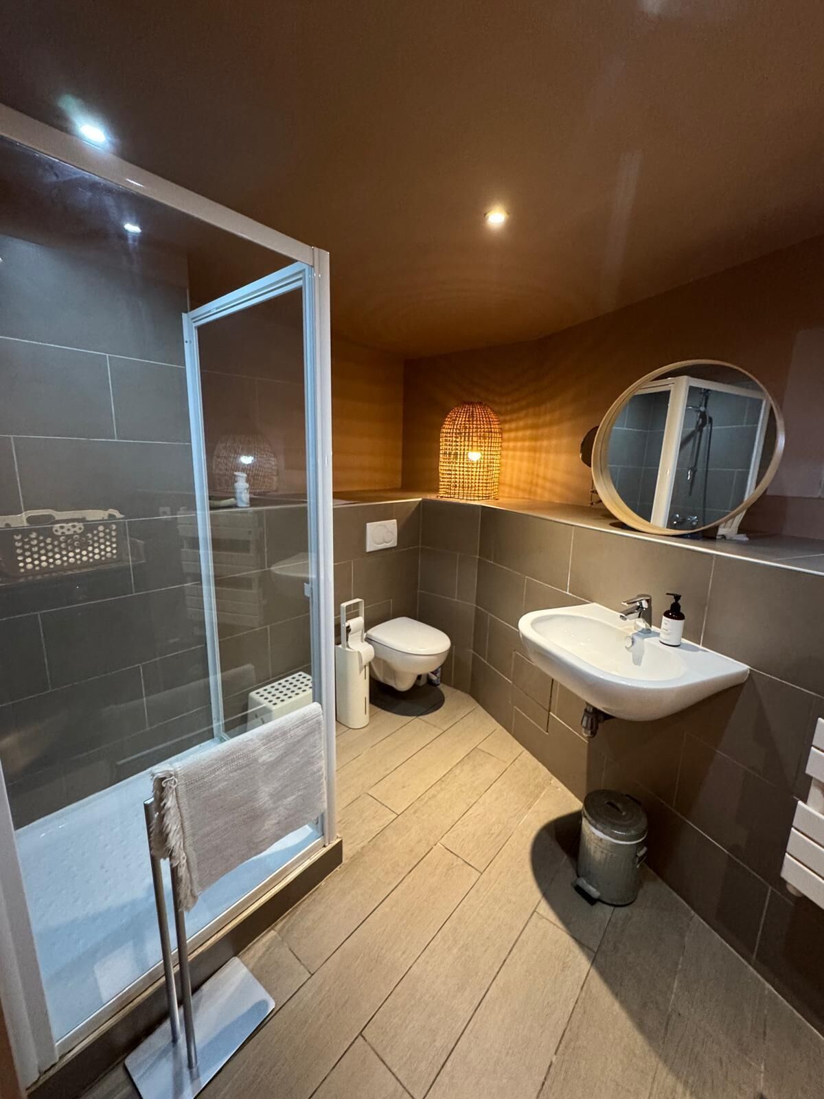 Une salle de bain moderne avec une douche à parois de verre, des toilettes, un lavabo et un miroir.