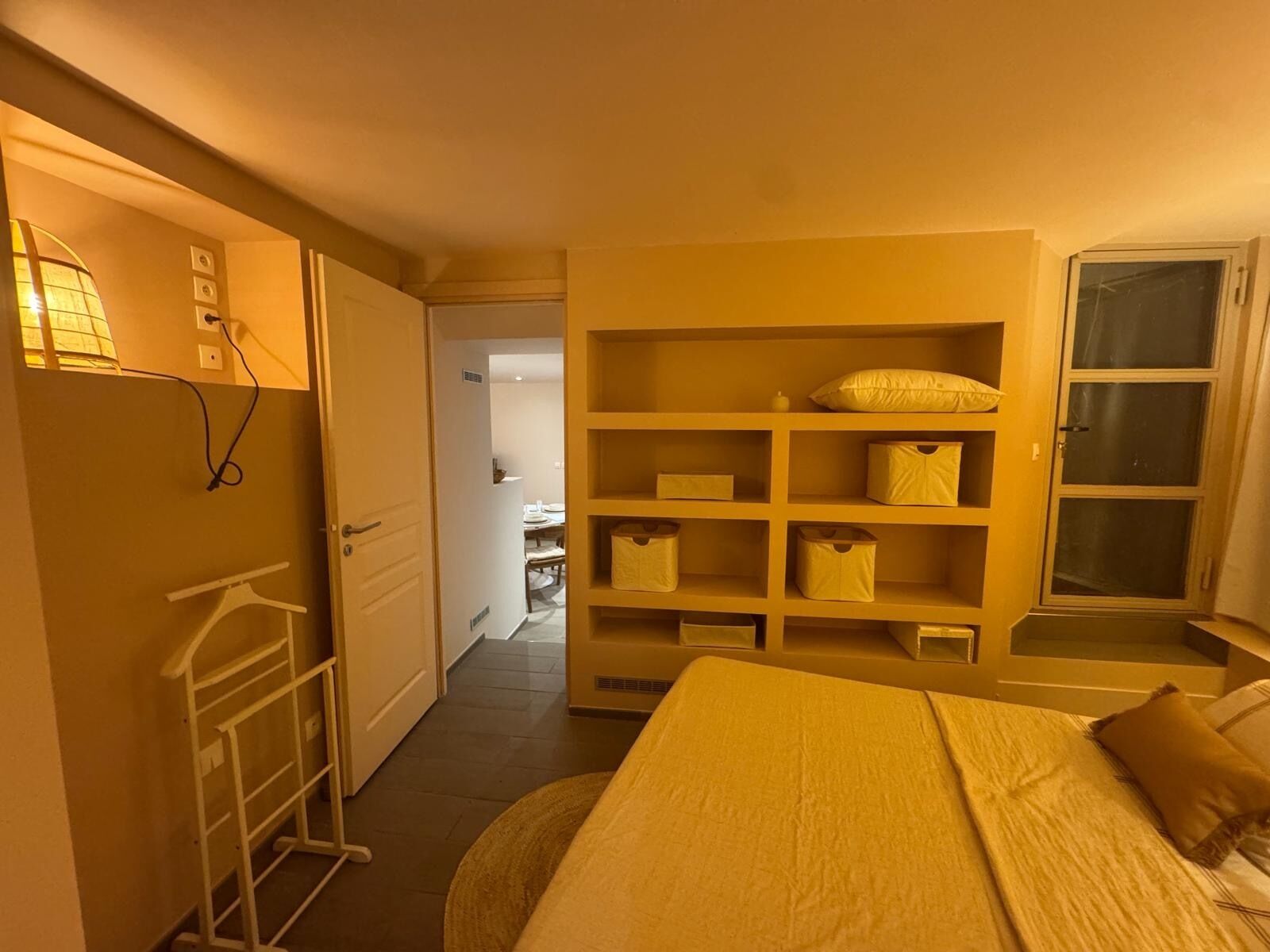 A hotel room with a bed, a wardrobe, a desk, and a window.