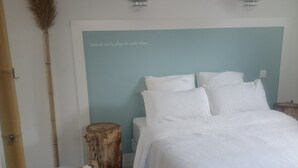 A bathroom with a wooden floor, a white bathtub, a wooden stool, a bamboo mat, and a wall-mounted towel rack. - Rental charming T2 Vendée 300m from the beach and 100 m from the forest (Saint-Jean-De-Monts)