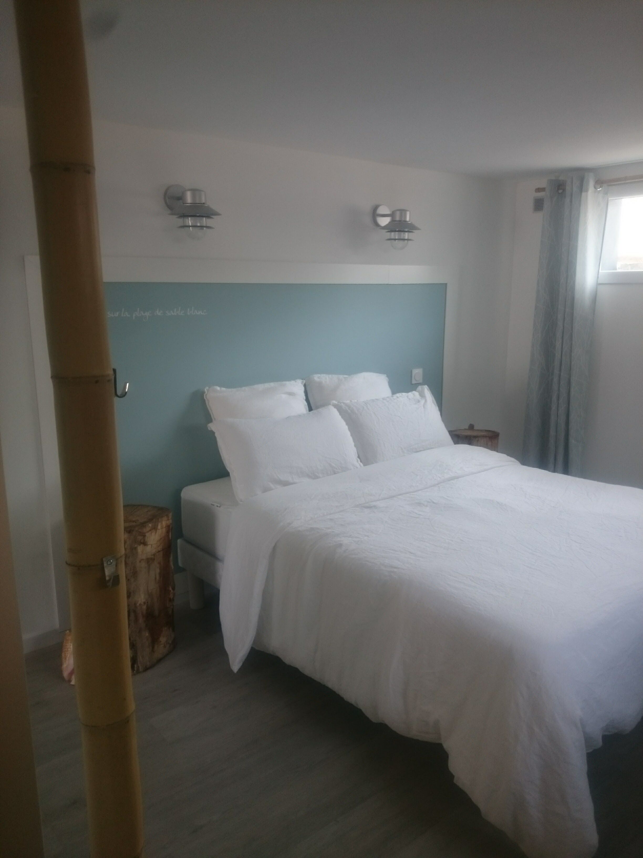 A hotel room with a bed, a small table, and a window.
