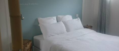 A hotel room with a bed, a small table, and a window.