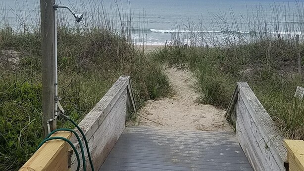 A wooden boardwalk leading to a beach with a cloudy sky. - Ocean Side Beach Condo in Family Friendly Community!  Oceanfront pool!! (Pine Knoll Shores)