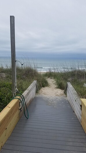 A wooden boardwalk leading to a beach with a cloudy sky. - Ocean Side Beach Condo in Family Friendly Community! Oceanfront pool!! (Pine Knoll Shores)
