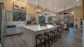 Cozinha espaçosa com uma ilha grande, iluminação pendente e vista para o exterior.