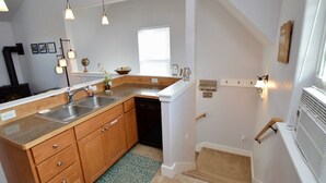 A kitchen with wooden cabinets, a dishwasher, and pendant lighting. - Carriage House Cutie (KING BED) -Steps From Lake & Park (Bozeman)