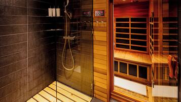 Un baño moderno con ducha de vidrio, suelo de madera y un reloj digital.