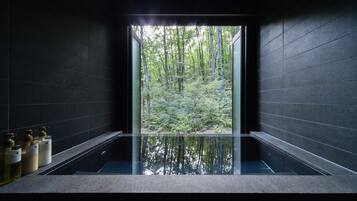 A modern bathroom with a glass enclosure, a bathtub, and toiletries on the counter.