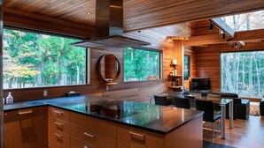 A modern kitchen with wooden cabinetry, a large island, and a built-in oven. - Phoenix Chalets (Hakuba)