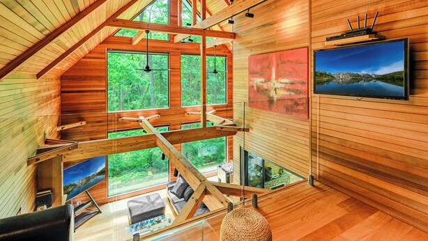 A modern interior with wooden beams, large windows, a flat-screen TV, and a cozy seating area. - Phoenix Chalets (Hakuba)