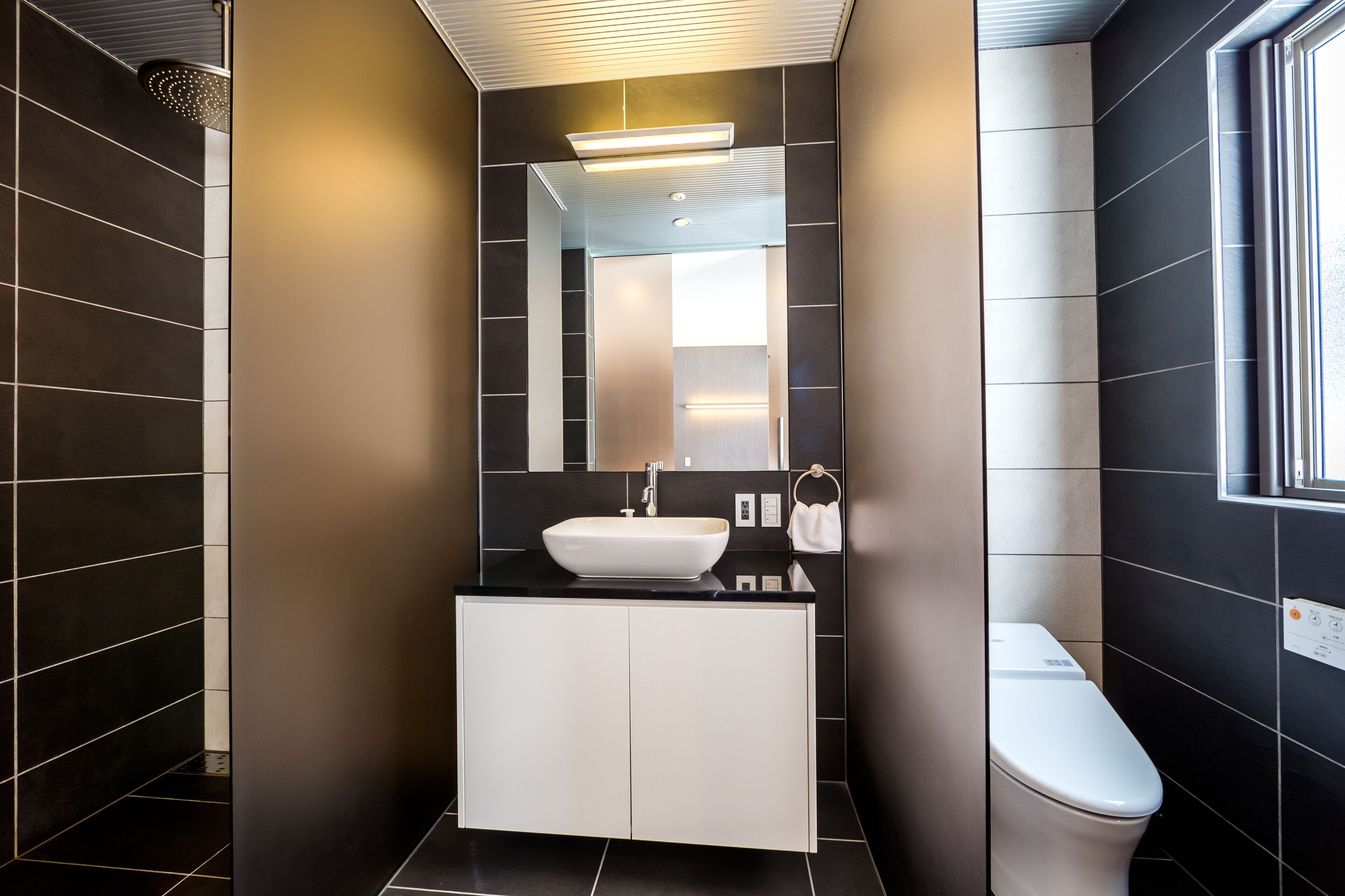Un baño moderno con un lavamanos blanco, un espejo y un inodoro.