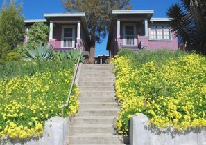Una escalera conduce a una casa flanqueada por un jardín de flores amarillas.