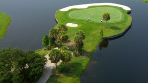 An aerial view of a golf course with a water hazard, sand bunkers, and a walking path. - Oceanfront/Beachfront -Sarasota Surf  Racquet - Y Building (Sarasota)