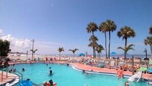 A pool area with palm trees, lounge chairs, and a clear sky. - Oceanfront/Beachfront -Sarasota Surf  Racquet - Y Building (Sarasota)