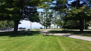 A park with picnic tables, a playground, and a view of the sea.