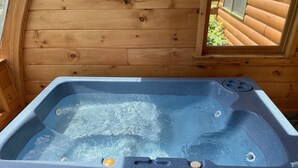 Un jacuzzi en una cabaña de madera con vista por la ventana.