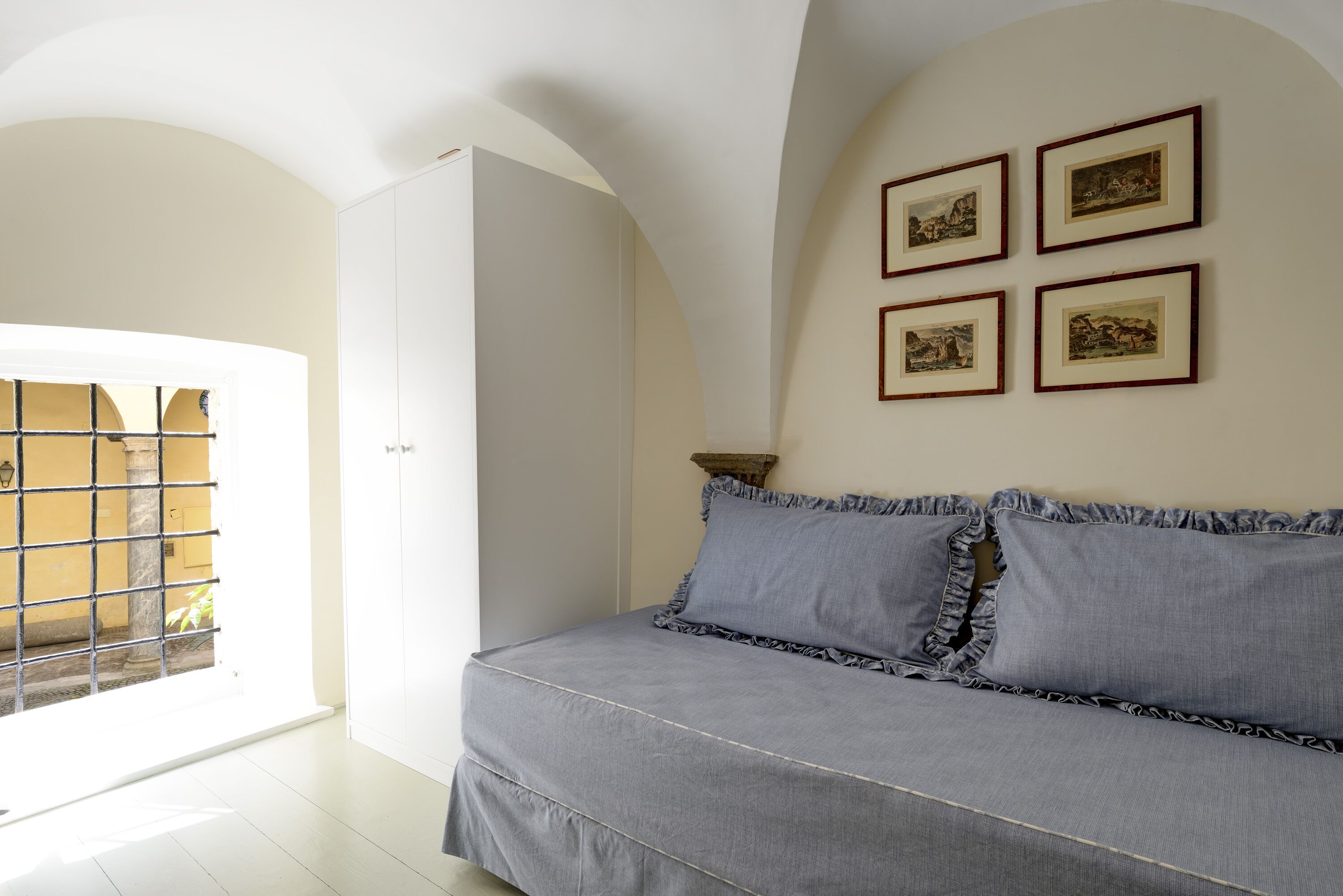 Un dormitorio con una cama, una ventana con vistas y cuatro cuadros en la pared.