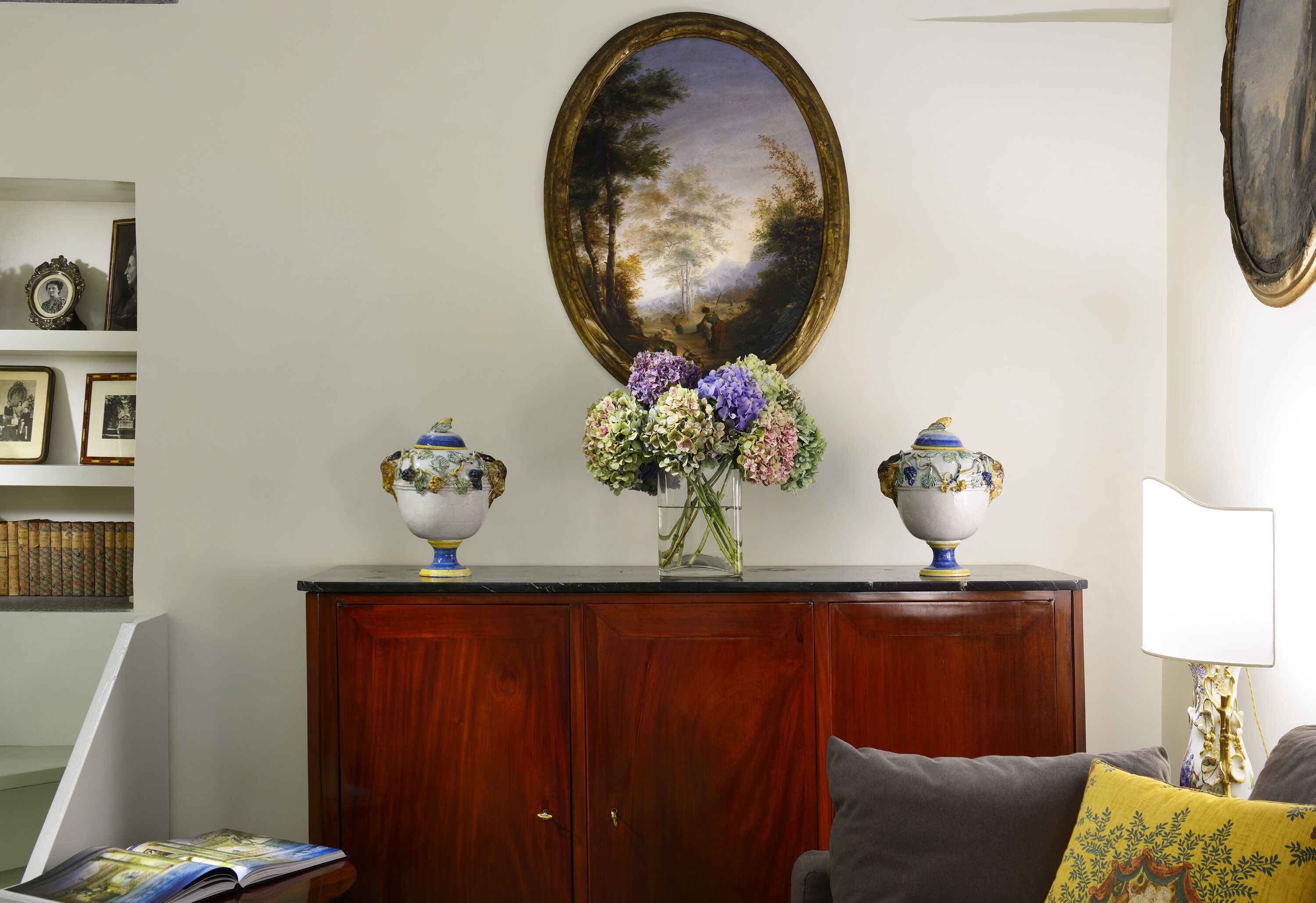Una stanza con un armadio in legno, un quadro incorniciato e un vaso con fiori.