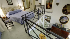 A bedroom with a bed, a chair, a desk, a staircase, and a wall with framed pictures. - Close To Piazza Navona, Historic, Charming & Romantic Flat, 2 Bath, AC, Wi-Fi (Roma)