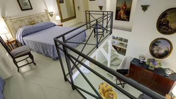 Una camera da letto con un letto, una sedia, una scrivania, una scala e una parete con quadri.