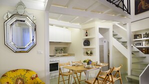 A dining area with a wooden table and chairs, a large mirror, and a staircase leading to an upper level. - Close To Piazza Navona, Historic, Charming & Romantic Flat, 2 Bath, AC, Wi-Fi (Roma)