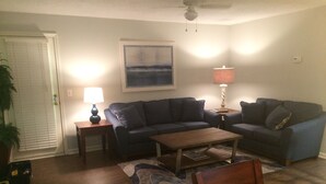 A living room with two sofas, a coffee table, a lamp, and a painting on the wall.
