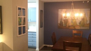 A dining area with a wooden table and chairs, a chandelier, and a painting on the wall.