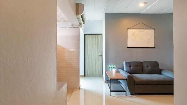 A modern living room with a grey sofa, a small table with bottles, and a world map on the wall. - Living Naraa Place (Bangkok)