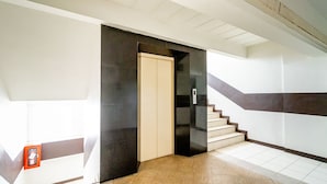 A modern interior with a staircase, a door, and a wall-mounted intercom. - Living Naraa Place (Bangkok)