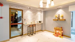 A modern kitchen with a brick wall backsplash, a microwave, and a small altar with decorations. - Living Naraa Place (Bangkok)