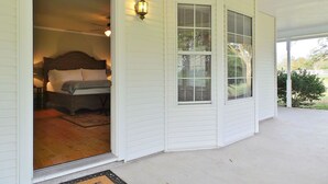 A room with a bed, a window with blinds, and a door leading to another room. - Rambling Ranch ~ The Ultimate Gathering Place! (College Station)