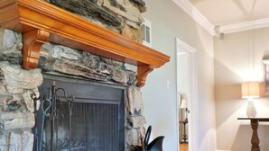 A stone fireplace with a wooden mantel, a fire screen, and a black pot on the hearth. - Rambling Ranch ~ The Ultimate Gathering Place! (College Station)
