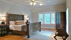 A bedroom with a large bed, a ceiling fan, and a view of the outdoors through a window. - Rambling Ranch ~ The Ultimate Gathering Place! (College Station)