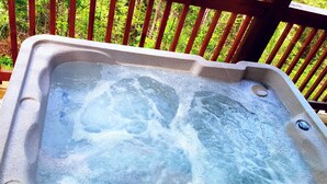 A hot tub on a wooden deck with a wooden railing in the background.