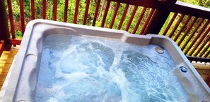 A hot tub on a wooden deck with a wooden railing in the background.