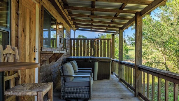 Une terrasse en bois dotée d’un espace salon couvert, comprenant une table et des chaises, et offrant une vue sur un paysage naturel.