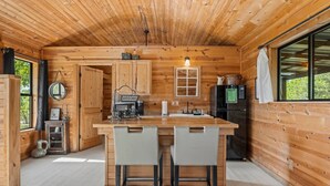 L’intérieur d’une cabane en bois comprend un coin cuisine, des murs en bois et une grande fenêtre.